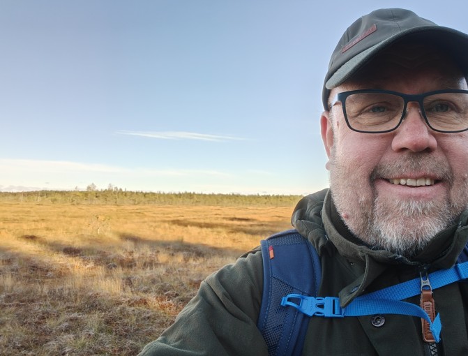 Keski-Suomen hyvinvointialueen työsuojeluvaltuutettu Asko Juuti hymyilee itse ottamassaan kuvassa syksyisessä maisemassa.