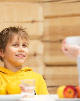 Lapsi hymyilee ruokapöydän ääressä.