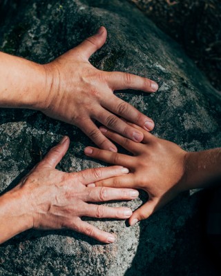 Ihmisten kädet luonnon kivillä.