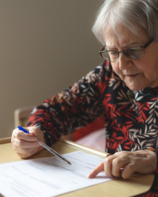 vanha nainen täyttää paperilomaketta