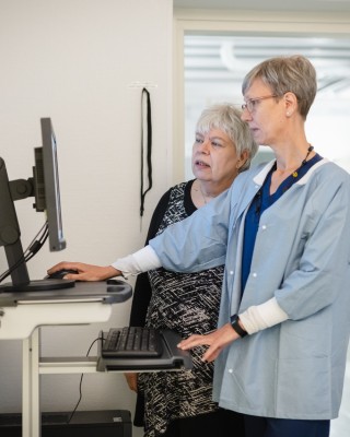 Hoitaja ja seniori katsovat tietokonetta