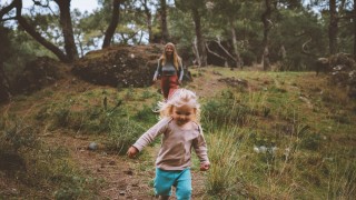 Aikuinen ja lapsi juoksevat metsässä.