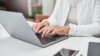 Iäkäs henkilö käyttää kannettavaa tietokonetta.