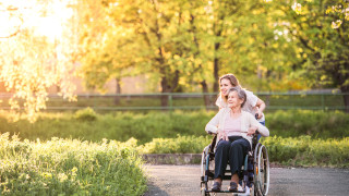 Ikäihminen ja hoitaja ulkoilemassa.