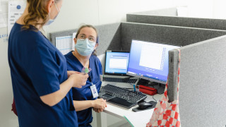 Kaksi sairaanhoitajaa keskustelevat tietokoneen ääressä.