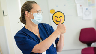 Ammattilainen näyttää peukkuja ja hymyilevaa kuva-emojia.