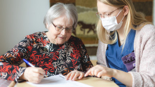 Kaksi naista juttelee ja täyttää lomaketta.