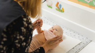 Vauva neuvolassa hoitopöydällä katselee terveydenhoitajaa.