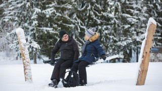 Kaksi henkilöä riippumatossa talvisissa maisemissa.