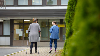 Asiakas ja ammattilainen kävelevät terveysasemalle.