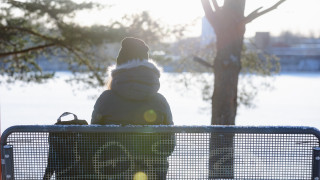 Nuori istuu penkillä auringossa.