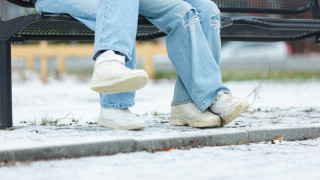 Nuoret istuvat puistonpenkillä, vain jalat näkyvät.