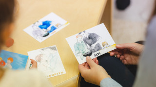 Kuvassa on kädet ja kädessä on kuvakortti.