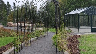 Käytävä ja kasvihuone puutarhamaisella pihamaalla