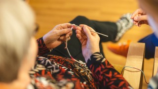 Henkilö kutoo puikoilla.