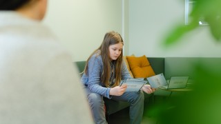 Nuori istuu sohvalla ja tutkii kortteja.