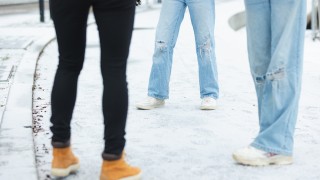 Kolme nuorta seisoo ulkona vastatusten, kuvassa näkyvissä vain kehon alaosa