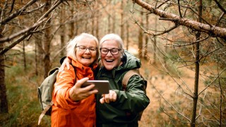 Kaksi henkilöä metsässä ottamassa selfietä.