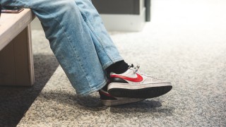 Nuori istuu penkillä lenkkarit jalassa.