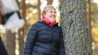 Nainen seisoo metsässä syyssäässä.