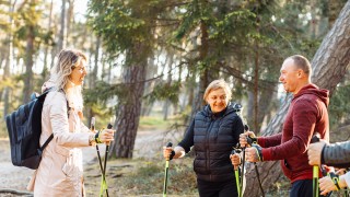 Kolme aikuista ulkona sauvakävelylenkille lähdössä.