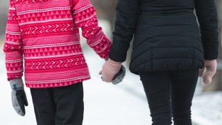 Aikuinen ja lapsi kävelevät käsi kädessä.