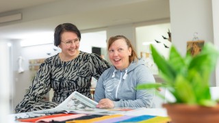 Asukas ja ohjaaja selaavat sanomalehteä pöydän ääressä