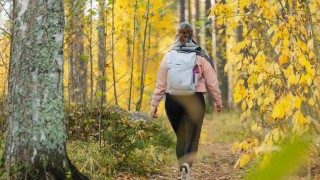 Ihminen kävelee reppu selässään syksyisessä metsässä.