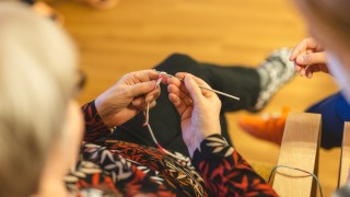 Iäkäs nainen tekee käsitöitä