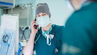 Leikkaava kirurgi puhuu puhelimeen leikkaussalissa