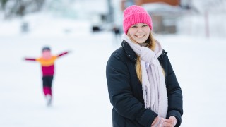 Hymyilevä aikuinen luistelemassa lapsen kanssa