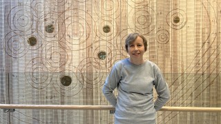 Kliinisen hoitotyön asiantuntija Anne Kanerva nojaa hymyillen puiseen kaiteeseen Sairaala Novassa.