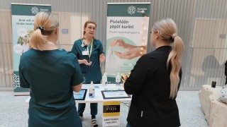 Infektiohoitaja Sari Pätsi kertoo STEPPI-päivien infektioiden torjunta -pisteellä kahdelle opiskelijalle käsihuuhteen oikeaoppisesta käytöstä. "Pistetään pöpöt kuriin!" kannustaa roll-up taustalla.