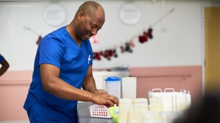 Sairaanhoitaja Fidele Sindayigaya valmistelee lääkejakoa hymy huulillaan.