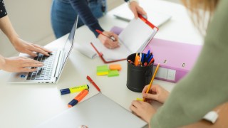 Kolme ihmistä työskentelevät pöydän ääressä