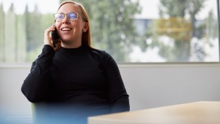 Iloinen ihminen puhelimessa.