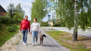 Aikuiset ja koira lenkkeilevät kesäisessä Keski-Suomessa.