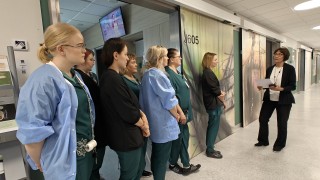 Sairaala Novan kotiutusyksikön työntekijät ovat kokoontuneet käytävälle ottamaan vastaan diplomin Kirsi Piitulaiselta.