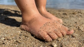 Paljaat jalat hiekkarannalla.