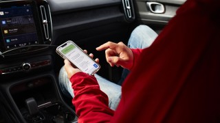 Henkilö on auton kyydissä ja katsoo älypuhelinta.