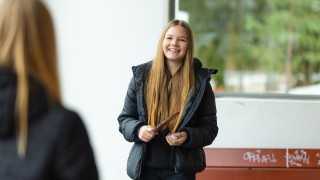 Pitkähiuksinen tyttö katsoo kuvan etualalla olevaa kaveriaan hymyillen