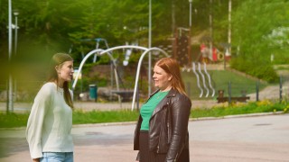 Kaksi naista keskustelevat leikkipuistossa.