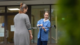 Keski-Suomen hyvinvointialueen ammattilainen auttaa asiakasta kävelysauvojen kanssa.