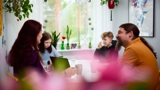 Perhe istuu pöydän ääressä keskustelemassa