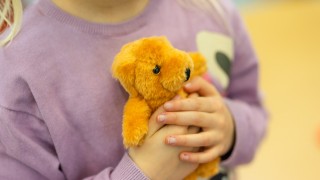 Lapsi puristaa pehmolelua rintaansa vasten.
