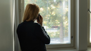 Henkilö puhuu puhelimessa ja katsoo ikkunasta ulos