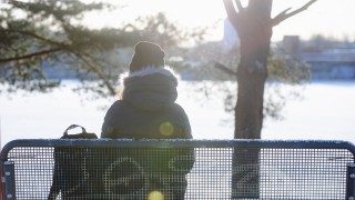 Henkilö istuu penkillä talvisessa ympäristössä