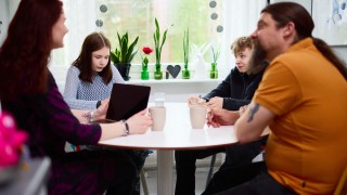 Perhe istuu keittiön pöydän ääressä