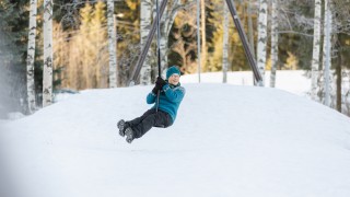 Henkilö keinuu keinussa talvella.