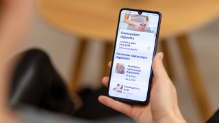 Henkilö pitää kädessään älypuhelinta, jossa näkyy digipolku